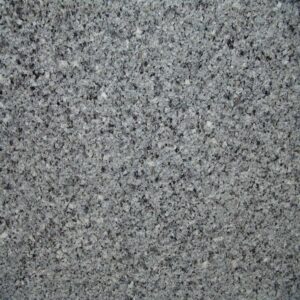 Close-up of a speckled gray granite surface, showing a mix of light and dark gray mineral patterns. The texture is rough and natural, typical of granite used in countertops or flooring.