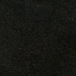 A close-up of a dark, textured surface with a grainy appearance. The material appears to be rough and solid, possibly stone or a similar composite. It has a uniform, deep black color throughout.