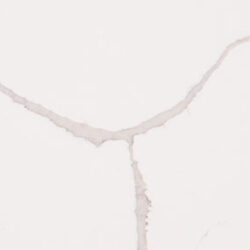 A white surface featuring natural cracks running vertically and horizontally, creating an abstract pattern. The cracks are light brown and irregular, giving the surface a textured appearance.