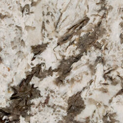 Close-up of a textured surface resembling granite, featuring a mix of light cream and brown tones with irregular dark brown veins and patches scattered throughout. The pattern is natural and uneven.