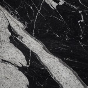 Dark marble surface with prominent white veining and patterns, creating a contrasting and textured appearance. The intricate lines give the stone a natural and organic look.