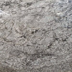 Close-up of a granite surface with intricate patterns. The stone features a mix of light and dark gray shades with swirling and speckled textures, creating a dynamic and natural appearance.