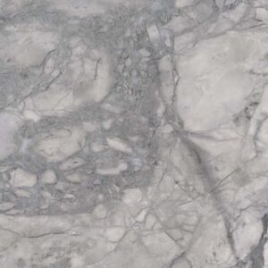 A close-up of a grey and white marble surface, showcasing intricate veining patterns. The stone texture has a mix of smooth and rough areas, with various shades of grey blending into white, creating a natural and elegant appearance.