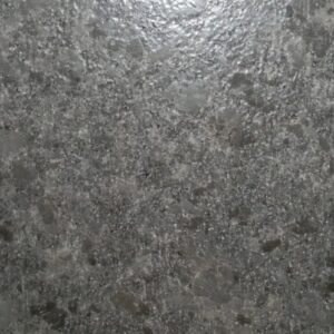 Close-up view of a textured gray granite surface with a pattern of dark and light speckles. The stone appears polished with a slight sheen.