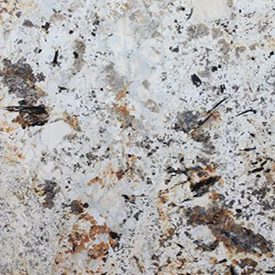 Close-up of a granite surface with a mix of white, black, and brown speckles and patterns, creating a textured appearance. The colors and mineral patterns are distributed irregularly, showcasing the natural stone formation.