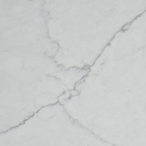 Close-up of a white marble surface with subtle gray veins forming intersecting lines and patterns. The texture is smooth and polished, highlighting the natural elegance of the stone.