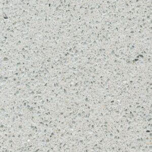 Close-up of a light gray terrazzo surface with various small, irregularly shaped speckles in different shades of gray, and subtle reflective fragments scattered throughout, creating a textured appearance.