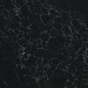 A close-up of a dark marble surface featuring a black background with intricate, irregular white veining patterns throughout. The texture appears smooth and polished.