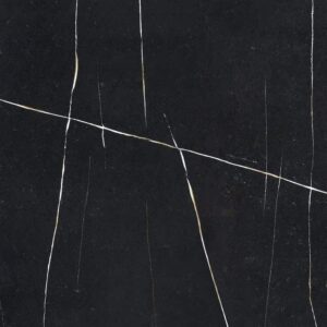 Close-up of a black surface with white, thin, irregular cracks running through it. The texture is smooth, resembling marble or stone, and the lines intersect at various angles, creating an abstract pattern.